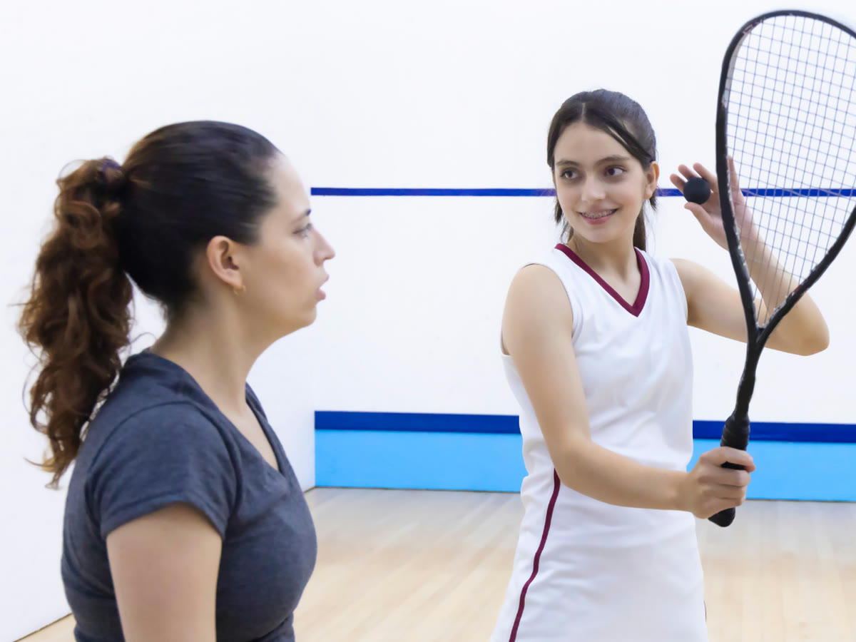 A squash coach and student mid-lesson on court